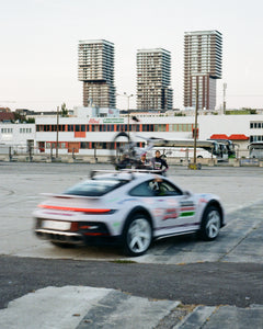 Team Motorhead Ferdi races through the shot in the 911 Dakar team car, tail lights glowing 