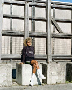 Dream Team member Niara at training camp resting on a concrete block wearing the Beyond Racing Dream longsleeve in black white silver graphics