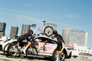 Racing Dream Team members Phil and Michi stretch next to the team car while Director Coco holds up the number four from the drivers seat, probably meaning how many hundreds of watts they aught to be doing