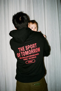 A snapshot of Marvin holding Romy over his shoulder while wearing TSOT sweater black.