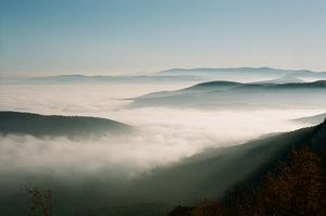  Mountain tops reaching through the fog as sunlight pours into a valley.